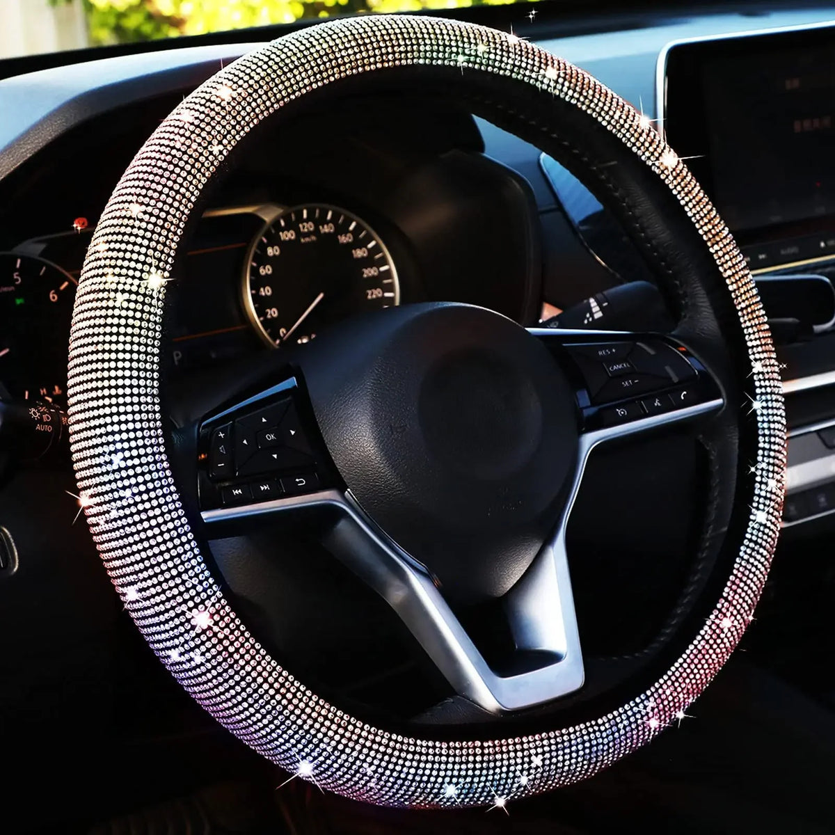 A close-up view of a black steering wheel covered in sparkling crystal diamond rhinestones inside a car interior.