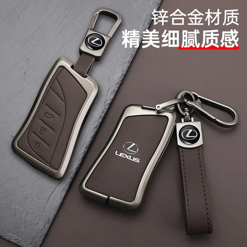A leather car key cover shell with a metal clasp and a brown leather strap, displayed on a gray surface.