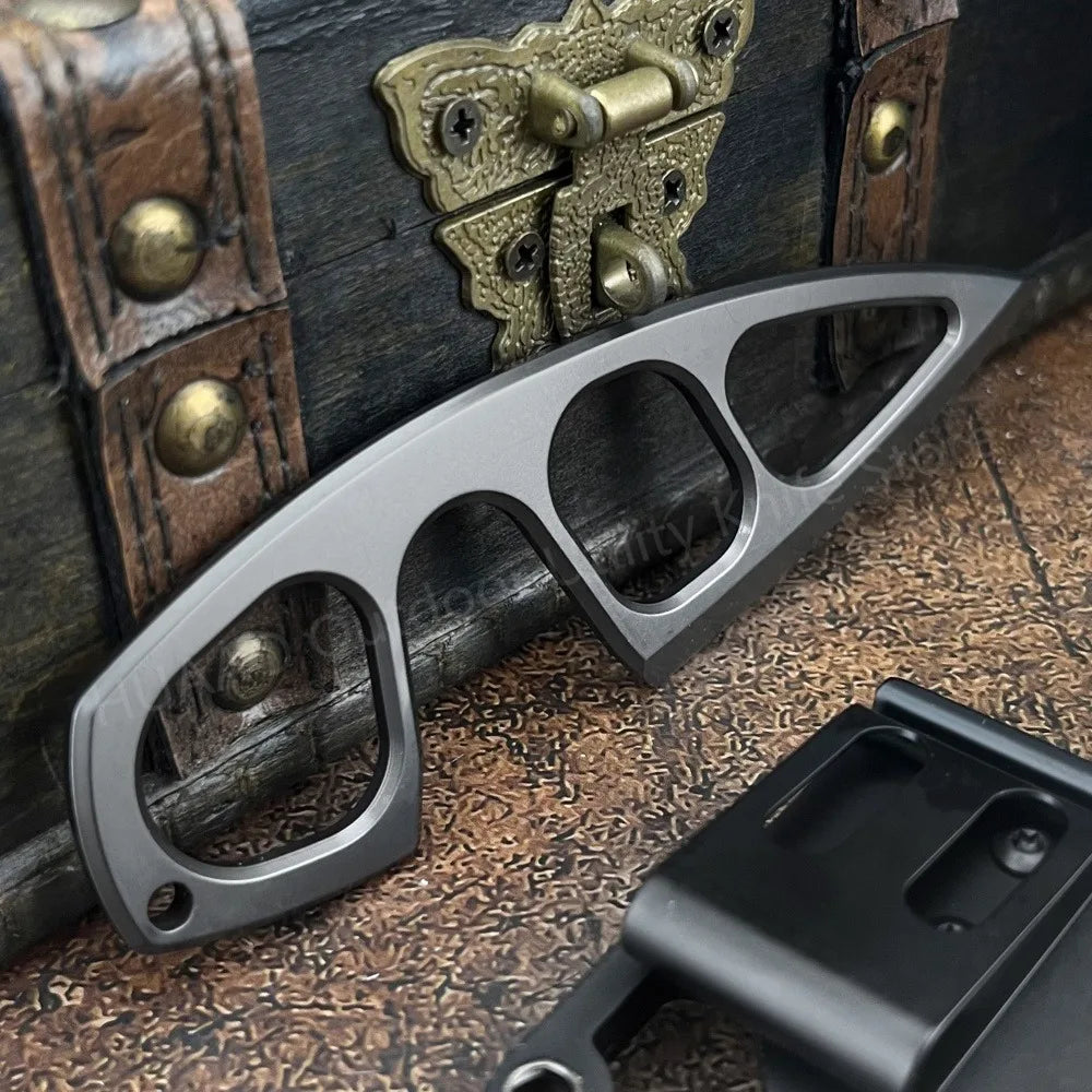 A silver fixed blade survival knife is shown next to an old leather box and a black tool.