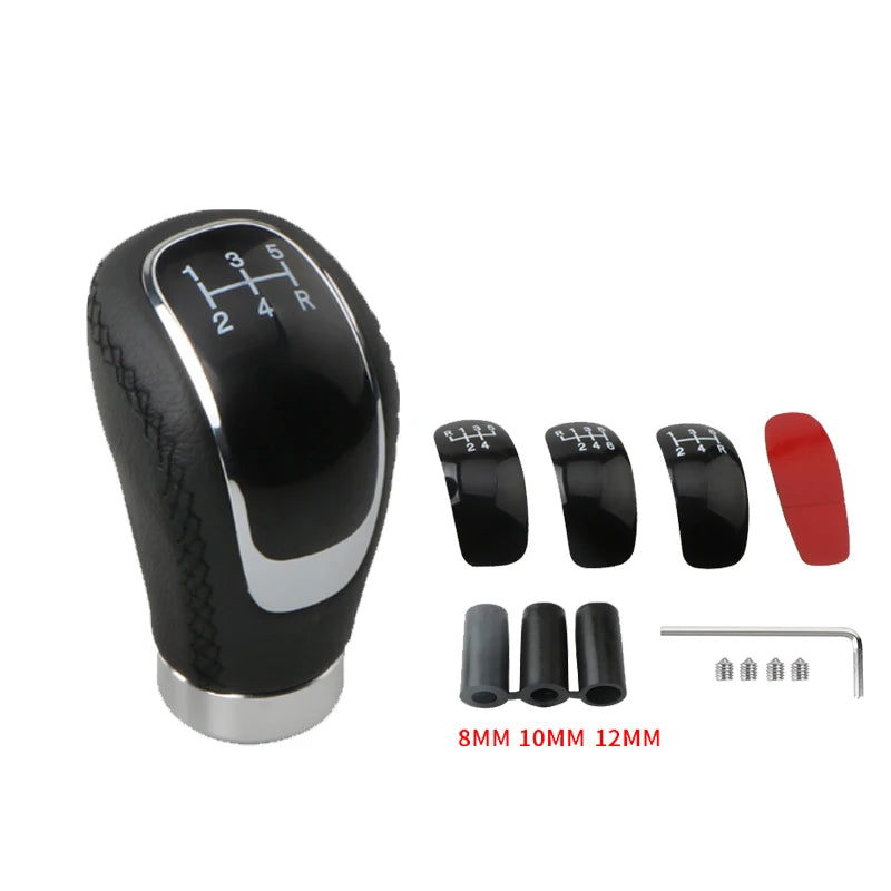 Black manual gear shift knob with interchangeable speed covers and mounting pins.