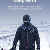 A person wearing a black windproof face mask and jacket is cycling in the snow.