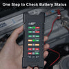 A hand holds a black battery tester device displaying various battery status indicators like Full, Good, Middle, and Low for 