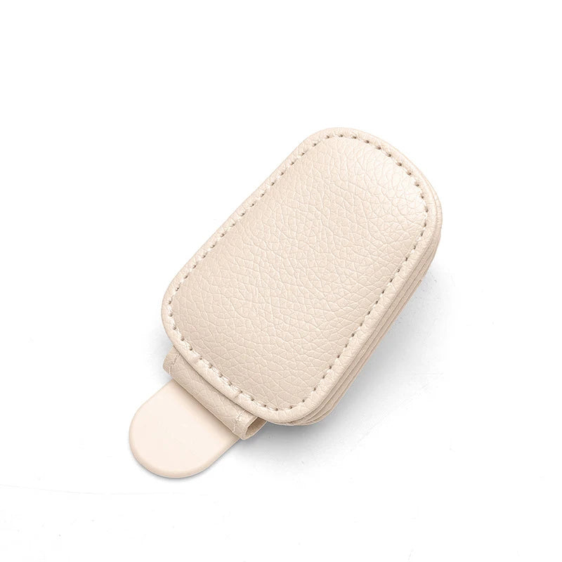 A beige magnetic leather sunglasses holder with a flexible silicone tip.