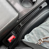 A black car seat gap filler organizer with a red button is shown in a close-up view.