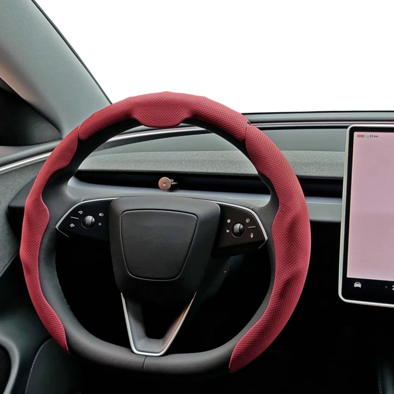 A close-up view of a red perforated leather steering wheel cover installed on a car's steering wheel.