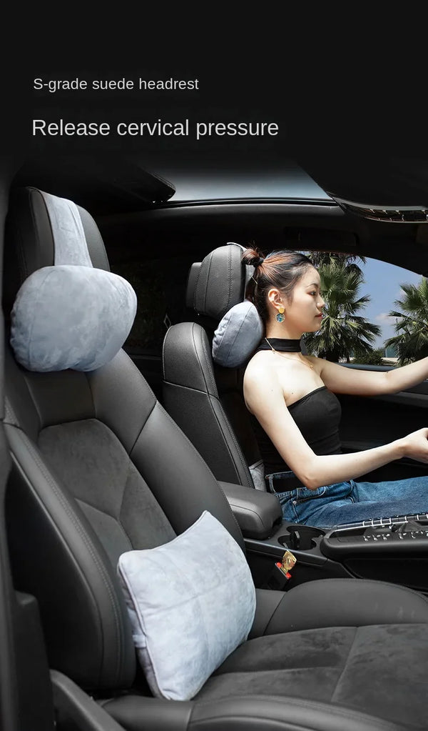 A woman is relaxing in a car seat with a suede headrest and neck rest cushion.