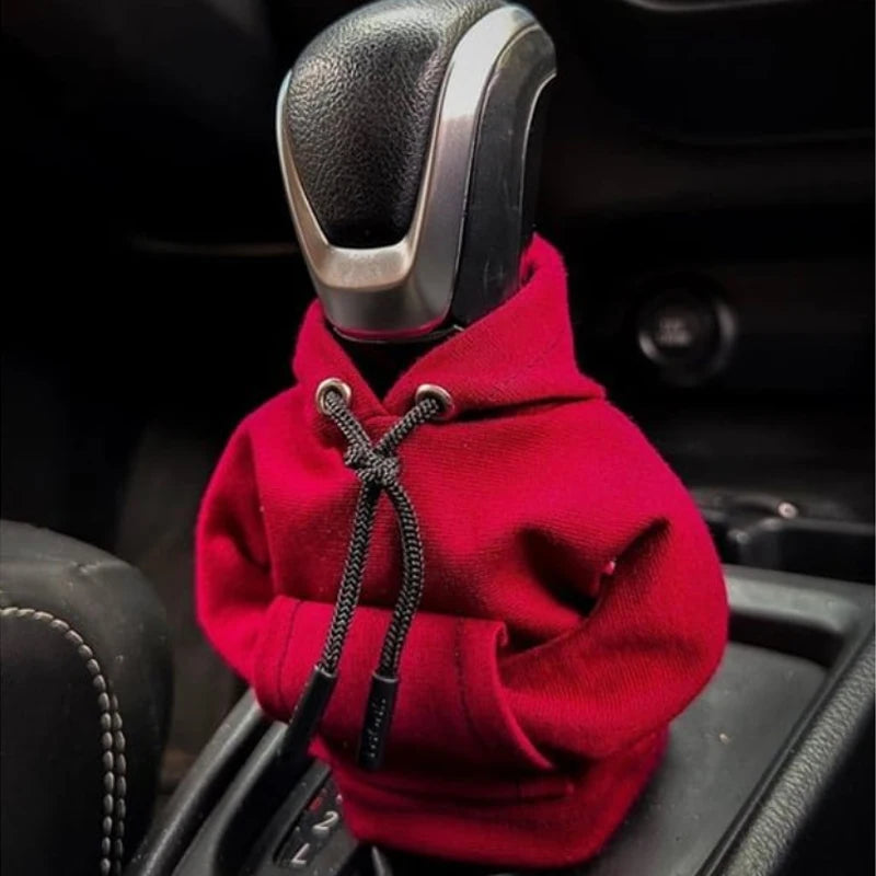 A red Gear Shift Hoodie cover is shown resting on a car gear shift.