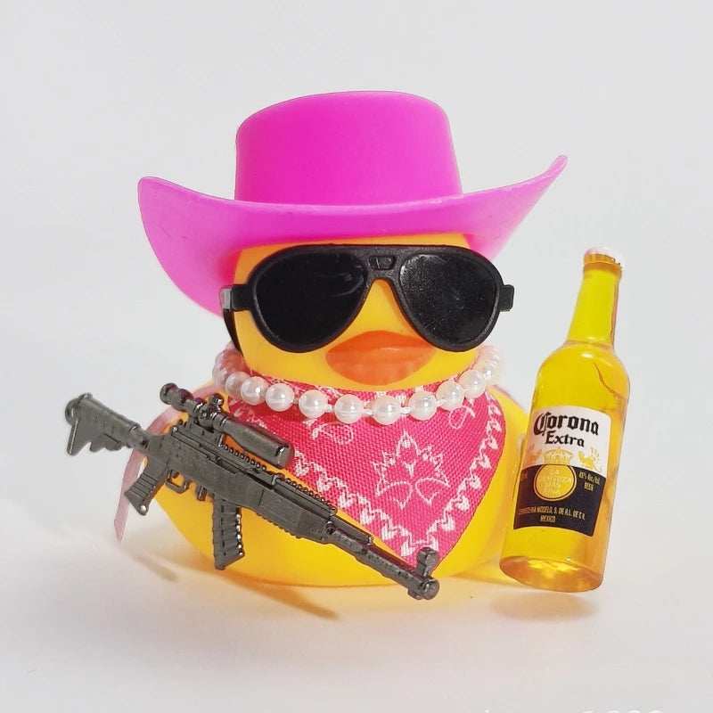 A yellow rubber duck wearing a pink sombrero and sunglasses is positioned next to a small firearm ornament.