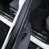 Close-up view of carbon fiber door sill protectors installed on a vehicle interior.