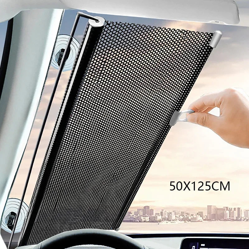 A hand is adjusting a black mesh retractable car windshield sun shade in a vehicle interior.