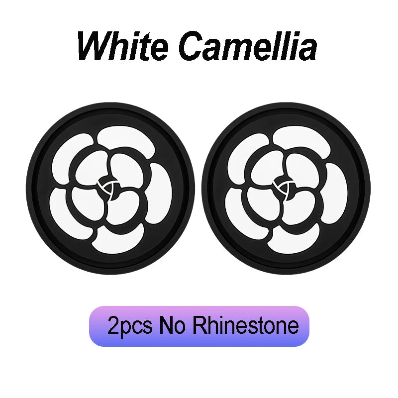 Two black coasters featuring a white camellia flower design, suitable for car cup holders.