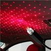 A portable LED star projector night light shining red dots onto a car's interior ceiling.