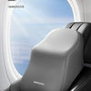 A close-up view of a gray ergonomic lumbar and neck support cushion placed on a dark leather seat inside an airplane window.
