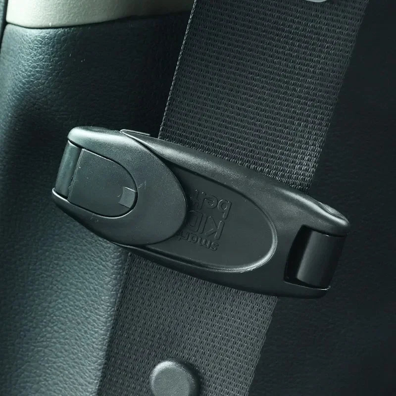 A black comfort-adjustable seat belt clip is shown attached to a dark automotive interior surface.