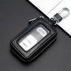 A black leather key protector pouch with a clear window and silver clasp resting on a dark surface.