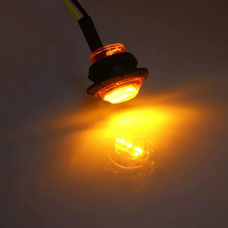 A round LED side marker light is shown illuminating a bright yellow glow against a dark background.