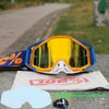 A pair of yellow and blue motocross goggles resting on a gray surface.