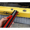 Une main tient une marchepied de porte en caoutchouc noir avec des accents rouges contre un corps de véhicule jaune.