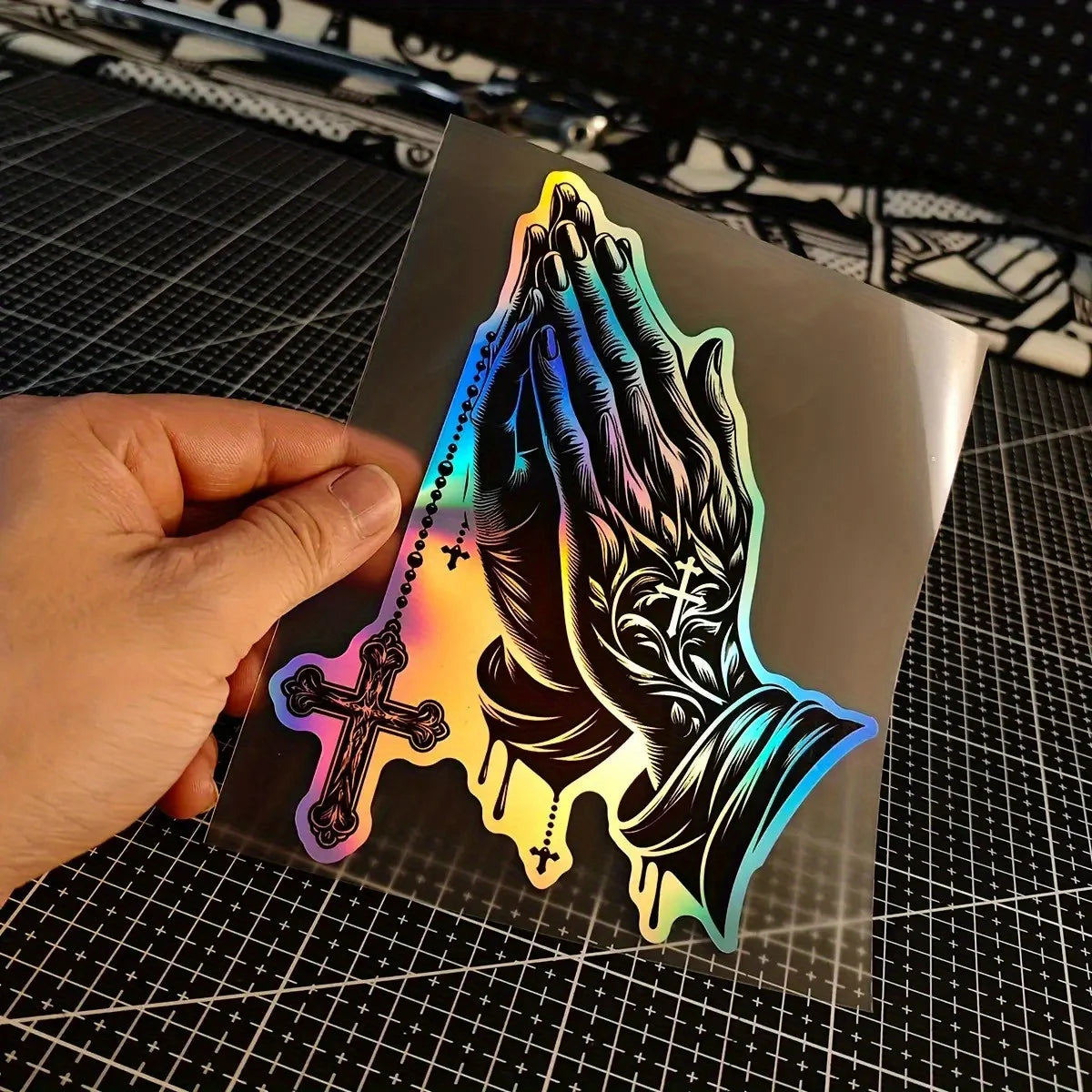 A glossy decal featuring a silhouette of praying hands with crosses and a rainbow gradient effect.