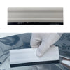 A white professional car window tint kit with a black edge is held by a gloved hand against a dark surface.