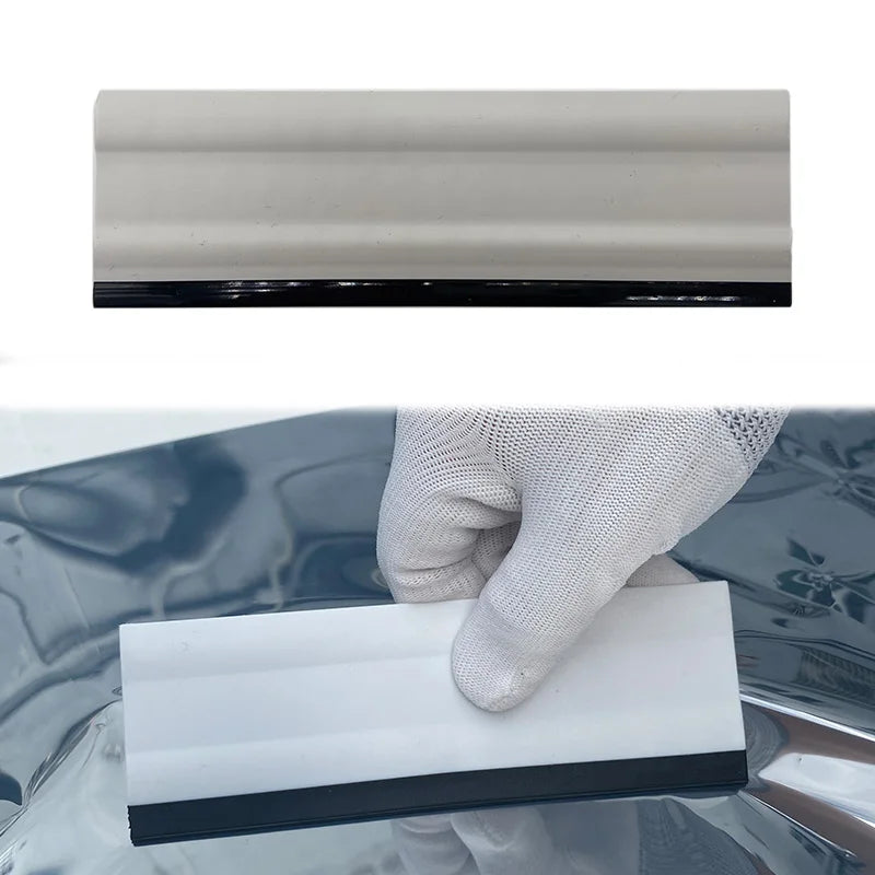 A white professional car window tint kit with a black edge is held by a gloved hand against a dark surface.