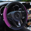 Close-up of a black steering wheel with a purple quilted leather cover and silver accents inside a car interior.