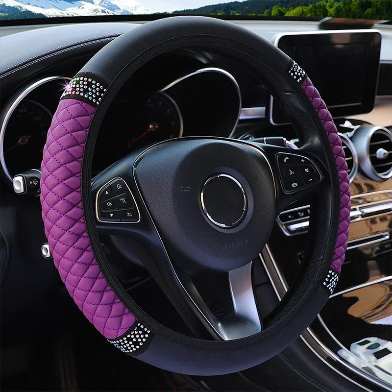 Close-up of a black steering wheel with a purple quilted leather cover and silver accents inside a car interior.
