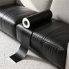 A roll of black self-adhesive PU leather repair patches is placed on a black leather seat cushion.