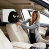 A woman is adjusting a black angry eyes car headrest cover in the interior of a car.