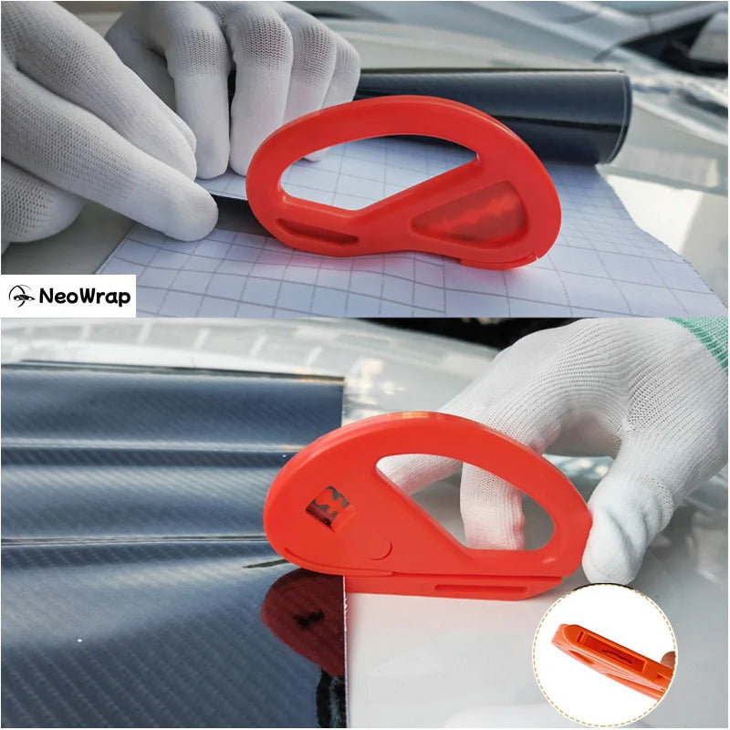 An orange plastic tool used for professional car window tinting, held by a gloved hand on a car surface.