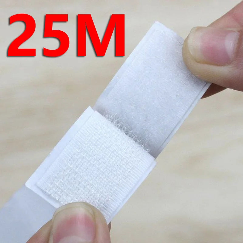 A hand is holding a white self-adhesive hook and loop tape strip for organization.