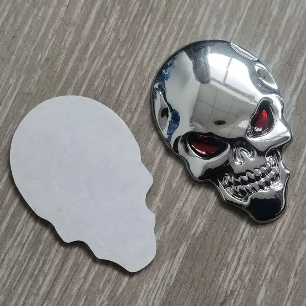 A chrome skull emblem badge with red eyes is shown next to a white silhouette of a human skull.