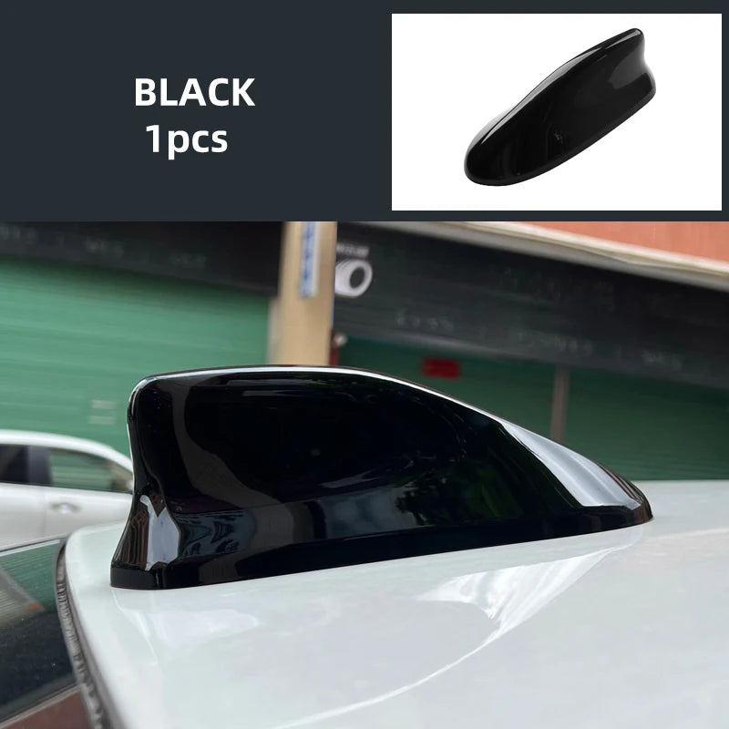 Black shark fin roof antenna cover installed on a white car.