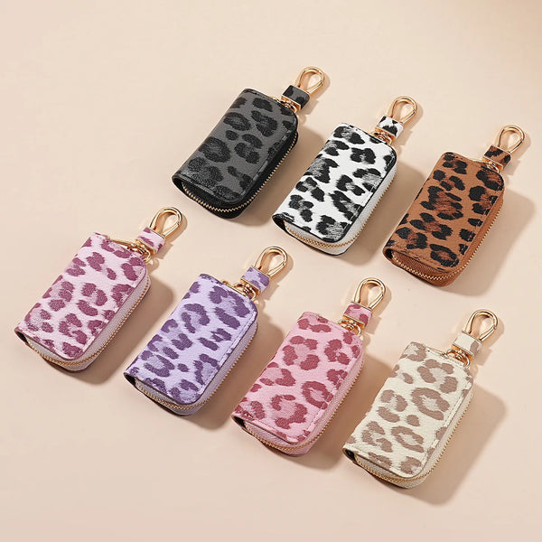 Una colección de porta llaves de coche con estampado de leopardo en varios tonos y acabados, dispuestos sobre un fondo claro.