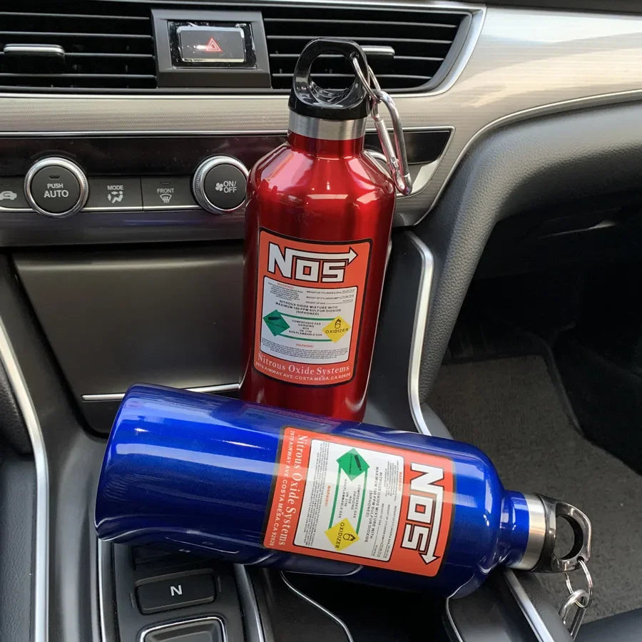 Two insulated stainless steel travel kettles, one red and one blue, are placed on a car dashboard.
