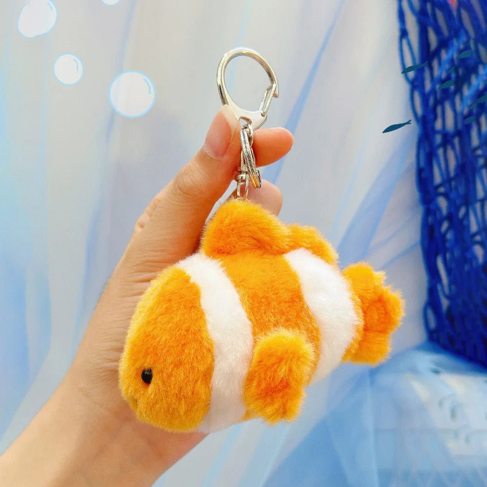 An orange and white plush bunny keychain with a gold ring is being held against a light blue background.