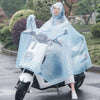 A woman wearing a transparent blue polka-dot windproof motorcycle rain poncho while sitting on a white scooter.