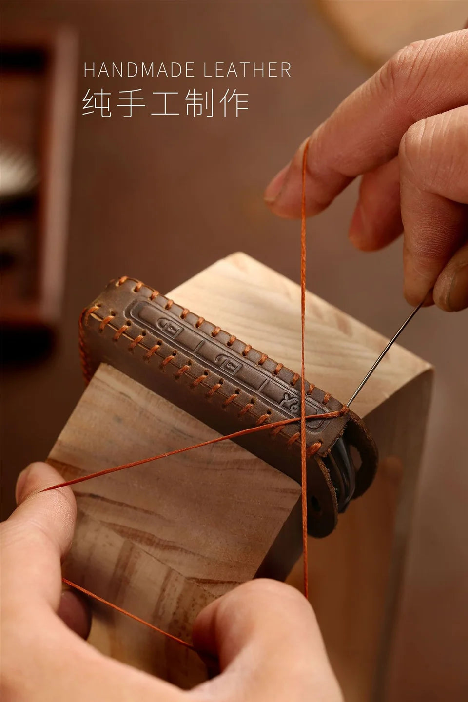 A hand is using a thin orange leather cord to attach a leather key fob cover to a wooden block.