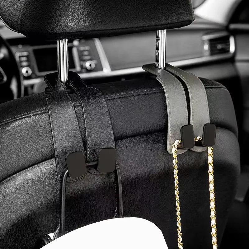 Black car headrest hooks with gold chains used for bag organization.