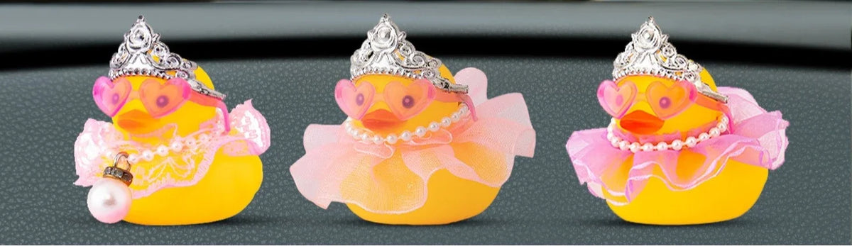 Three decorative rubber duck toys in yellow and pink with sparkling crowns and pearl necklaces.