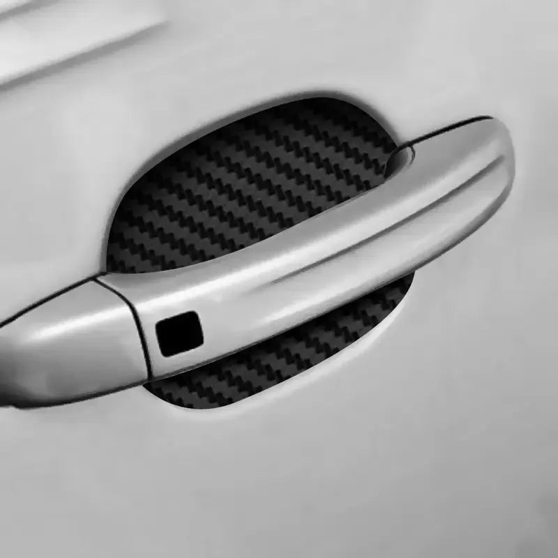 A close-up view of a chrome car door handle protected by a black carbon fiber film.