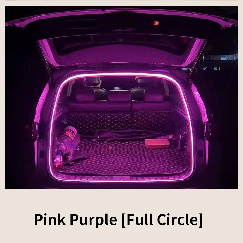 Vue intérieure du coffre d'une voiture avec une bande lumineuse LED rose-violet illuminant l'espace.