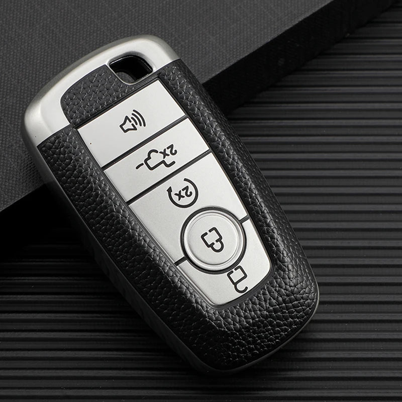 A silver multi-function key fob holder with four buttons rests on a dark, textured surface.