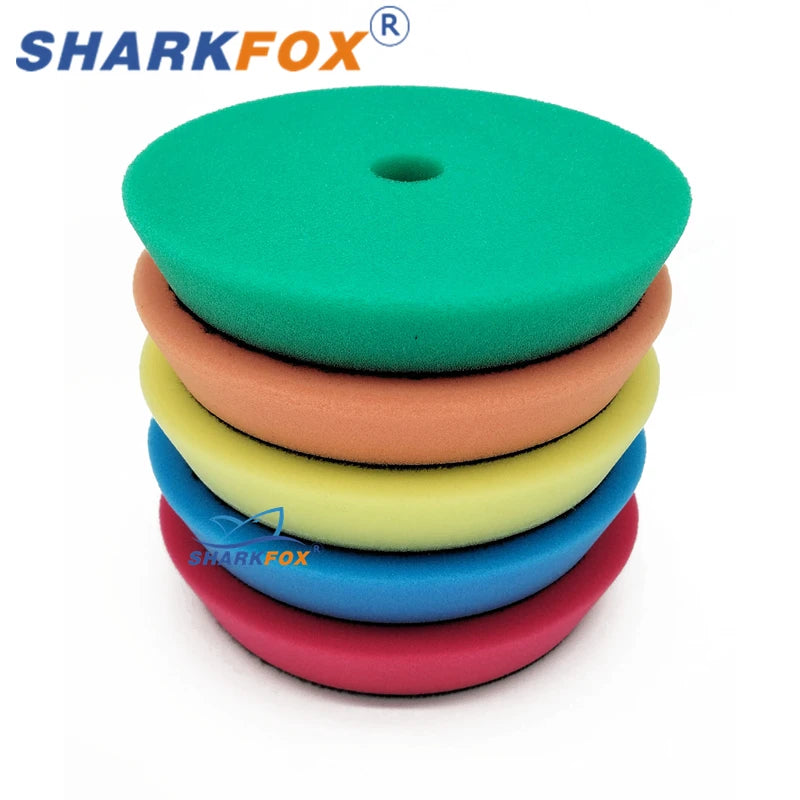 A stack of green, orange, yellow, and blue polishing sponge pads for car buffing.