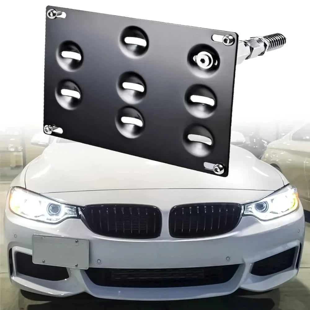 A black license plate mount with multiple holes is shown attached to the front of a white BMW car.