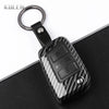 A black carbon fiber button cover for a car key, attached to a metal keyring.