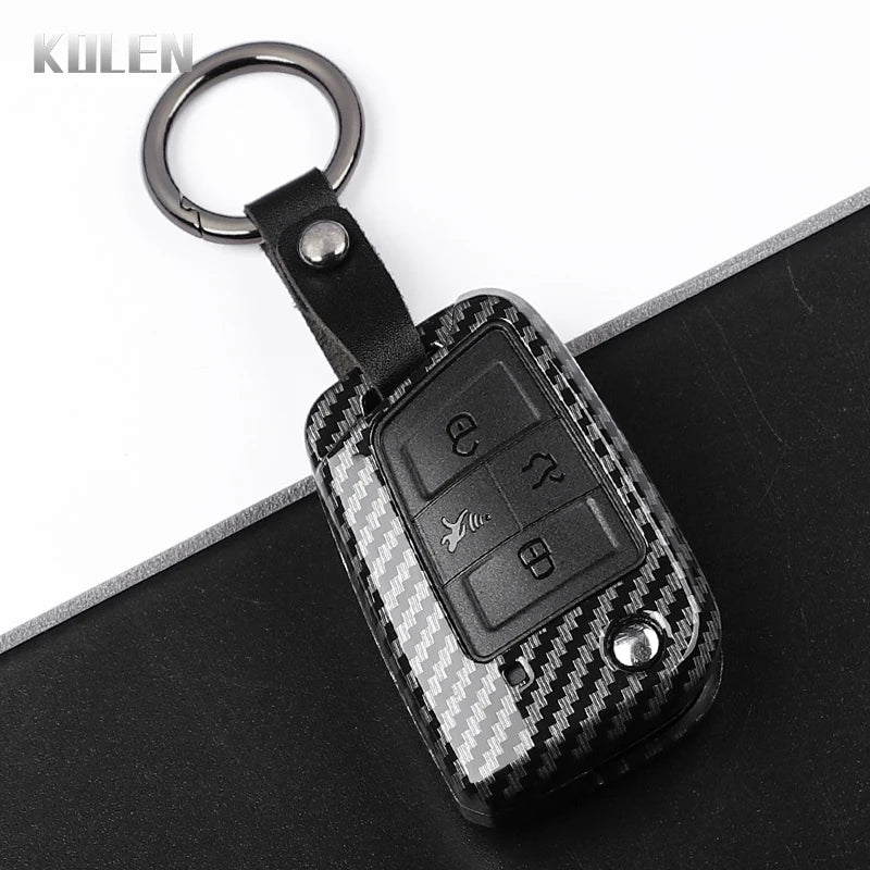 A black carbon fiber button cover for a car key, attached to a metal keyring.