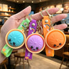 A hand holds several colorful silicone keychains shaped like cute bao buns with rainbow accents.