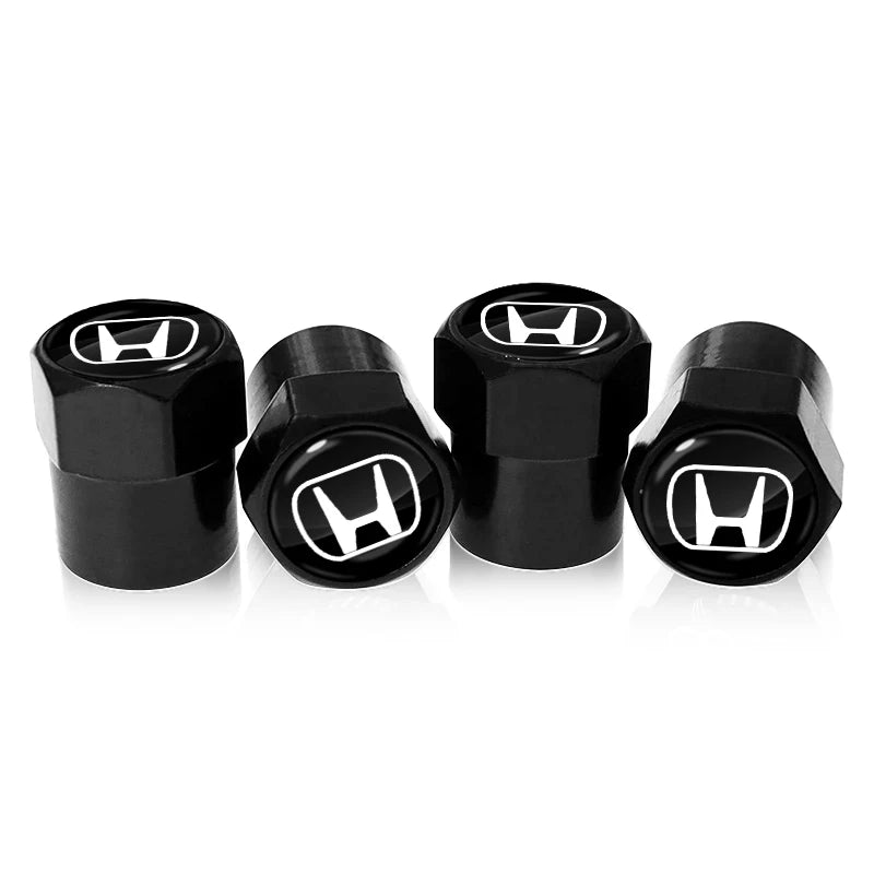 A set of four black anodized tire valve caps with chrome lettering.