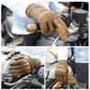 A close-up of tactical hard-shell gloves with a touchscreen grip being used on a motorcycle handlebar.
